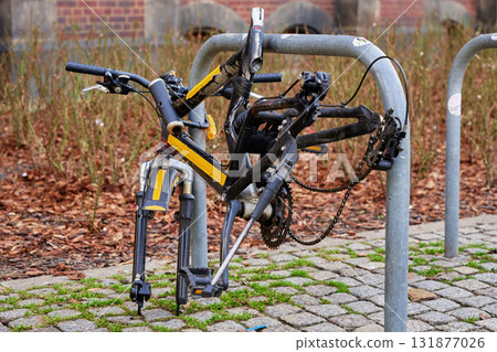 Damaged bicycle frame locked to bike rack on city street 131877026