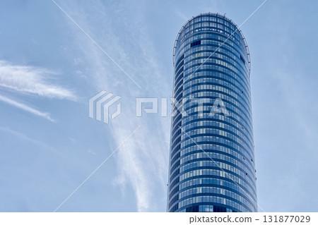 Modern glass skyscraper tower against blue sky 131877029