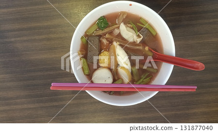 Spicy seafood soup with fish cake slices, tofu and vegetables in red broth served with chopstick and spoon, warm and savory comfort meal Spicy seafood soup with fish cake slices, tofu and vegetables in red broth served with chopstick and spoon, warm and savory comfort meal 131877040