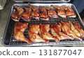 Smoked roasted duck leg quarter on metal rack, savory golden glaze and crispy skin, appetizing outdoor barbecue presentation 131877047