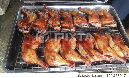 Smoked roasted duck leg quarter on metal rack, savory golden glaze and crispy skin, appetizing outdoor barbecue presentation Smoked roasted duck leg quarter on metal rack, savory golden glaze and crispy skin, appetizing outdoor barbecue presentation 131877047