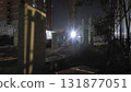 Abandoned construction site urban night concrete pillar security light metal fence scaffolding shadow pattern highrise building overgrown 131877051