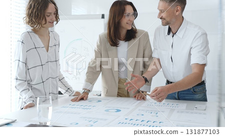 Professional team reviewing financial data, collaborating on working documents, demonstrating team achievements and positive dynamics in the workplace. Business people concept 131877103