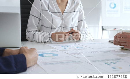 Business meeting with colleagues discussing charts and graphs, analyzing financial reports and strategy plans, teamwork collaboration in modern office setting Business meeting with colleagues discussing charts and graphs, analyzing financial reports and strategy plans, teamwork collaboration in modern office setting 131877288