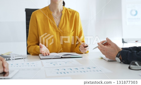 Business professionals discussing charts and graphs, analyzing data and collaborating on strategic project in modern corporate workspace 131877303