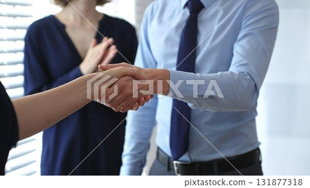 Business people shaking hands during a successful corporate meeting, symbolizing strong teamwork while standing in bright office 131877318