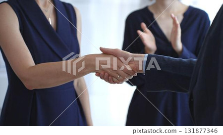 Business woman and businessman in blue jacket shaking hands, concluding a deal, and celebrating success with an agreement and partnership in a corporate office. Business people concept Business woman and businessman in blue jacket shaking hands, concluding a deal, and celebrating success with an agreement and partnership in a corporate office. Business people concept 131877346