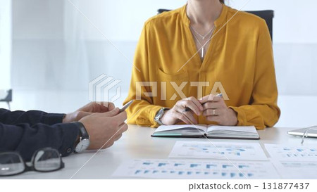 Business people team collaborating and analyzing financial data while taking notes during a corporate meeting in a modern office Business people team collaborating and analyzing financial data while taking notes during a corporate meeting in a modern office 131877437