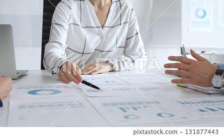 Business team meeting with financial documents and charts, discussing data analysis, planning strategies, and corporate success during collaborative teamwork session 131877443