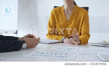 Business people team collaborating and analyzing financial data while taking notes during a corporate meeting in a modern office Business people team collaborating and analyzing financial data while taking notes during a corporate meeting in a modern office 131877456
