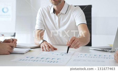 Business team reviewing financial charts, collaborating intently around conference table in contemporary workspace, sharing insights during strategic planning session in office meeting room Business team reviewing financial charts, collaborating intently around conference table in contemporary workspace, sharing insights during strategic planning session in office meeting room 131877463