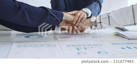 Teamwork and business collaboration with colleagues joining hands over financial charts, symbolizing unity, partnership, success, and strategic corporate planning Teamwork and business collaboration with colleagues joining hands over financial charts, symbolizing unity, partnership, success, and strategic corporate planning 131877465