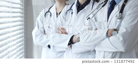 A team of doctors in white lab coats standing with arms crossed demonstrates experience, unity, and the essence of medicine in a modern clinic A team of doctors in white lab coats standing with arms crossed demonstrates experience, unity, and the essence of medicine in a modern clinic 131877492