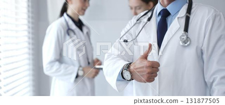 Doctor giving thumbs up sign for medical approval while standing with health practitioners, symbolizing trust in healthcare, patient well being, and successful treatment Doctor giving thumbs up sign for medical approval while standing with health practitioners, symbolizing trust in healthcare, patient well being, and successful treatment 131877505