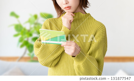 A woman thinking while looking at her bankbook 131877547