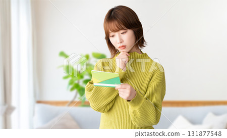 A woman thinking while looking at her bankbook 131877548
