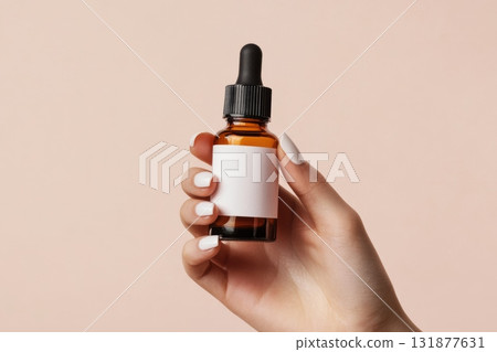 Dark amber glass bottle in female hand. Natural skin care SPA beauty product design. Mineral organic oil cosmetics on beige background. Mock-Up. Oily pipette. Face and body treatment. Blank logo label 131877631