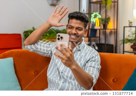Indian man on video chat with friend laughs waves hello goodbye shows ok sign during chat smiles fun 131877714