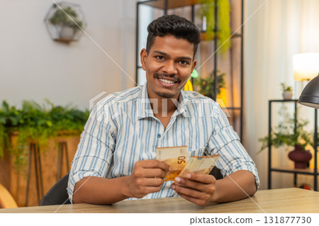 Indian man counts euro cash bonus salary plans invest smiles proud income wealth profit success joy Indian man counts euro cash bonus salary plans invest smiles proud income wealth profit success joy 131877730