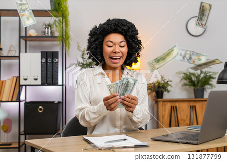 African American businesswoman joyfully throws cash in air celebrating big bonus lottery win success 131877799