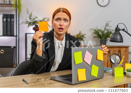 Young businesswoman stressed by sticky notes on laptop tosses notes fearing unfinished tasks today Young businesswoman stressed by sticky notes on laptop tosses notes fearing unfinished tasks today 131877803