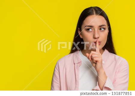 Woman placing finger on lips showing silence gesture asking for quiet serious thoughtful expression 131877851