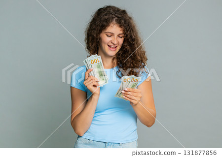 Woman counting cash dollars money happily satisfied celebrating salary savings financial earnings 131877856