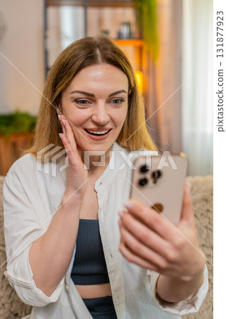 Adult happy woman celebrating lottery win on smartphone smiling with joy and making victory gesture 131877923
