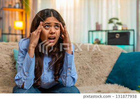 Indian woman touching head with tension and pain from headache at home, exhausted and uncomfortable 131877938