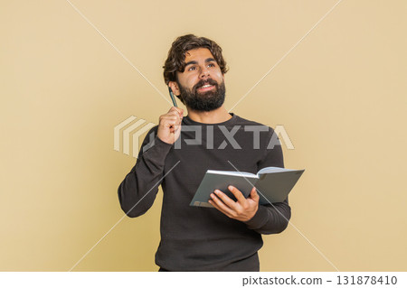 Thoughtful businessman making notes, writing down thoughts with pen into diary on beige background Thoughtful businessman making notes, writing down thoughts with pen into diary on beige background 131878410