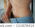 Close-up of a boy who shows that his jeans are too big for him, due to the fact that he has lost weight 131878414
