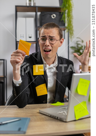 Tired exhausted businessman with laptop sticky notes with many tasks sitting at home office desk Tired exhausted businessman with laptop sticky notes with many tasks sitting at home office desk 131878435
