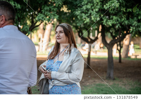 Woman in light blue floral dress standing in green park on sunny day Woman in light blue floral dress standing in green park on sunny day 131878549