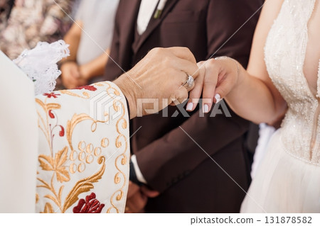 Orthodox Wedding Ceremony Ring Exchange: Priest, Bride, Groom, White Dress, Hands, Faith, Symbolism, Celebration, Gold, Elegant, Traditional 131878582