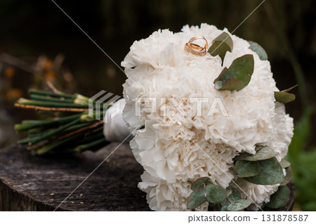 Wedding Rings on White Carnation Bouquet. Romantic Ceremony, Gold Bands, Florals, Love, Marriage, Celebration, Soft Focus, Natural Light Photography 131878587