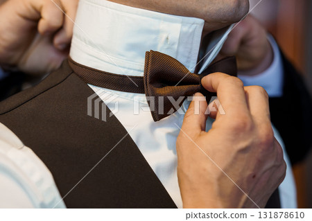 Elegant Wedding Groom Bow Tie Adjustment, Brown Texture, Formal Attire, Hands Helping, Classic Style, Tuxedo, Ceremony Preparation, Close-Up Shot Elegant Wedding Groom Bow Tie Adjustment, Brown Texture, Formal Attire, Hands Helping, Classic Style, Tuxedo, Ceremony Preparation, Close-Up Shot 131878610