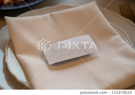 Elegant Table Setting with Folded Napkin and Place Card at Fine Dining Restaurant. Cream Colors, Soft Textures. Elegant Table Setting with Folded Napkin and Place Card at Fine Dining Restaurant. Cream Colors, Soft Textures. 131878628