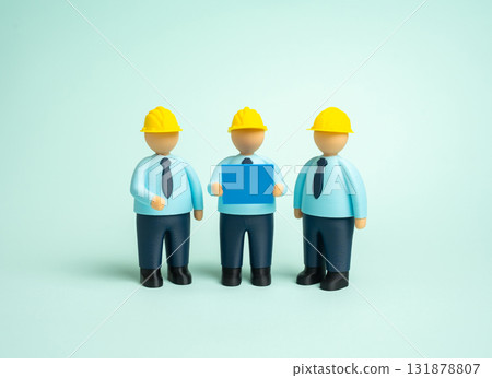 Builders in hard hats and with blue prints. Designers, builders and engineers. Concept of teamwork, professional collaboration, and construction industry standards. Builders in hard hats and with blue prints. Designers, builders and engineers. Concept of teamwork, professional collaboration, and construction industry standards. 131878807