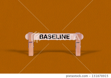 Baseline symbol. Wooden stick tightened by Clothespins, beautiful Orange color Backdrop. Business and Baseline concept with copy space Baseline symbol. Wooden stick tightened by Clothespins, beautiful Orange color Backdrop. Business and Baseline concept with copy space 131878915