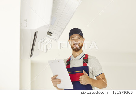Happy technician approving air conditioner installation, checking split system indoor unit installed 131879366