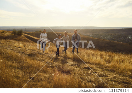 Positive happy family running outdoors, feeling free and relaxed in nature, posing on meadow 131879514