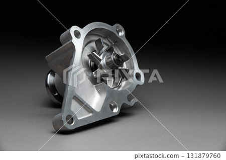 A new, shiny aluminum engine coolant pump on a gray gradient background. Contrast backlighting. A new, shiny aluminum engine coolant pump on a gray gradient background. Contrast backlighting. 131879760