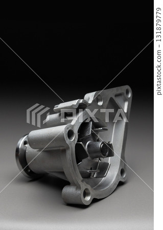 A new, shiny aluminum engine coolant pump on a gray gradient background. Contrast backlighting. A new, shiny aluminum engine coolant pump on a gray gradient background. Contrast backlighting. 131879779