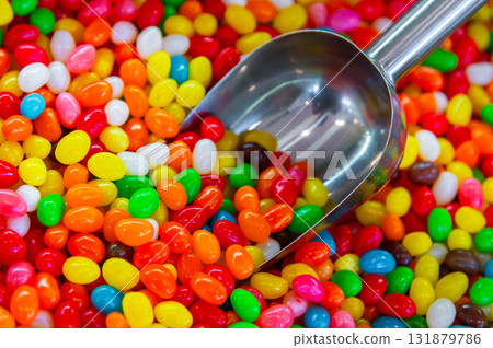 Pile of colorful glazed dragees. Shiny candies in a sugar crust. A background A metal spoon on the right is dipped into the glazed or chocolate-covered nuts Pile of colorful glazed dragees. Shiny candies in a sugar crust. A background A metal spoon on the right is dipped into the glazed or chocolate-covered nuts 131879786