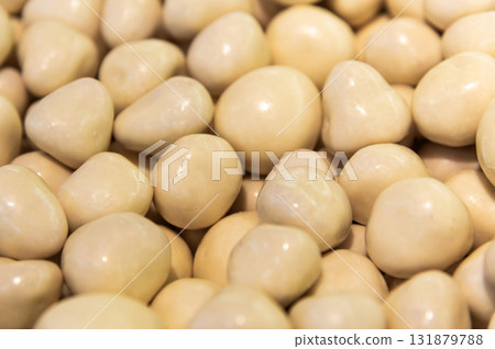 pile of candied almond dragees serves as a backdrop. Handmade nut candies in white chocolate pile of candied almond dragees serves as a backdrop. Handmade nut candies in white chocolate 131879788