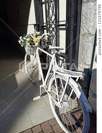 white decorative bicycle with flowers in busket on enter to shop. sunny day white decorative bicycle with flowers in busket on enter to shop. sunny day 131879798