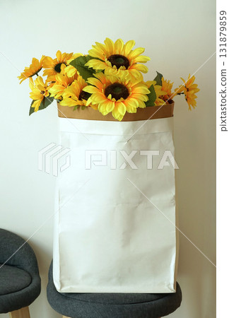 artificial sunflower In an empty paper bag for storing content, Place on a chair for a vintage style home or shop decoration. 131879859