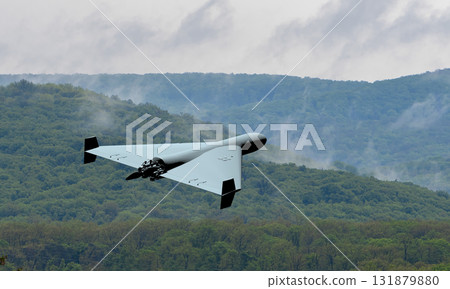 A military kamikaze drone flies against a backdrop of mountains and clouds. A military kamikaze drone flies against a backdrop of mountains and clouds. 131879880