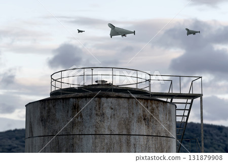 A group of drones flies over the industrial area of the plant and tanks 131879908