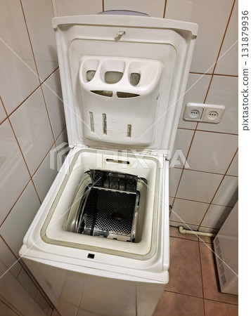 Top-loading washing machine with the open lid stands in the bathroom 131879936